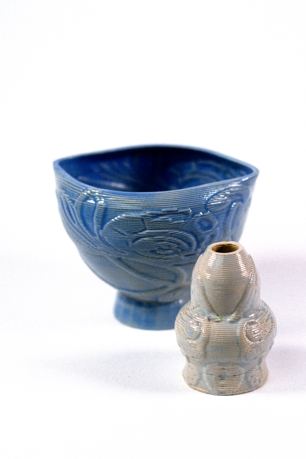 A blue 3D-printed clay ceremonial matcha bowl next to a textured whisk holder, featuring digital floral patterns designed by GLINA3.