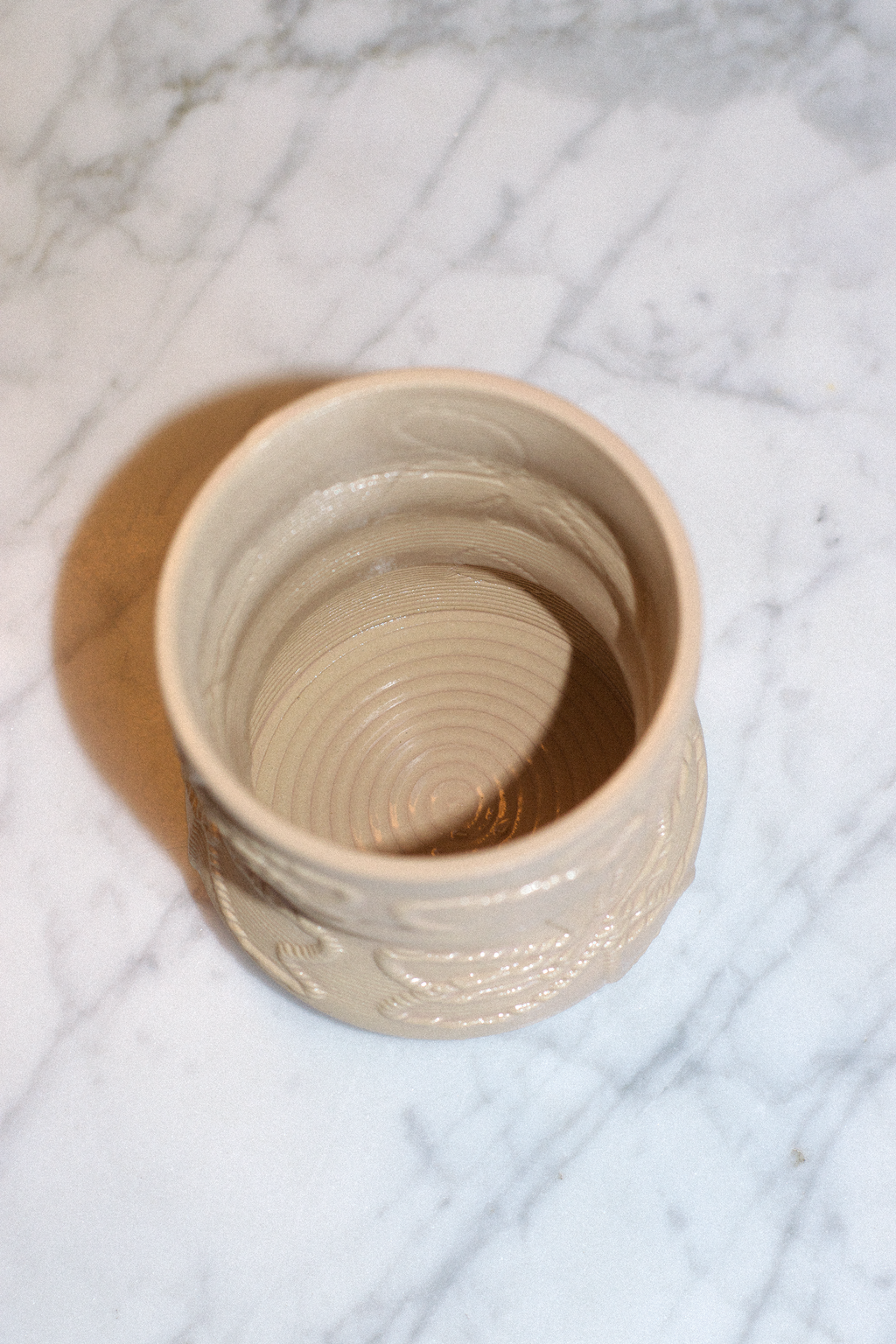 Top-down view of a cashew 3D-printed clay matcha cup by GLINA3 on a marble surface, highlighting the unique spiraled texture on the inside bottom.