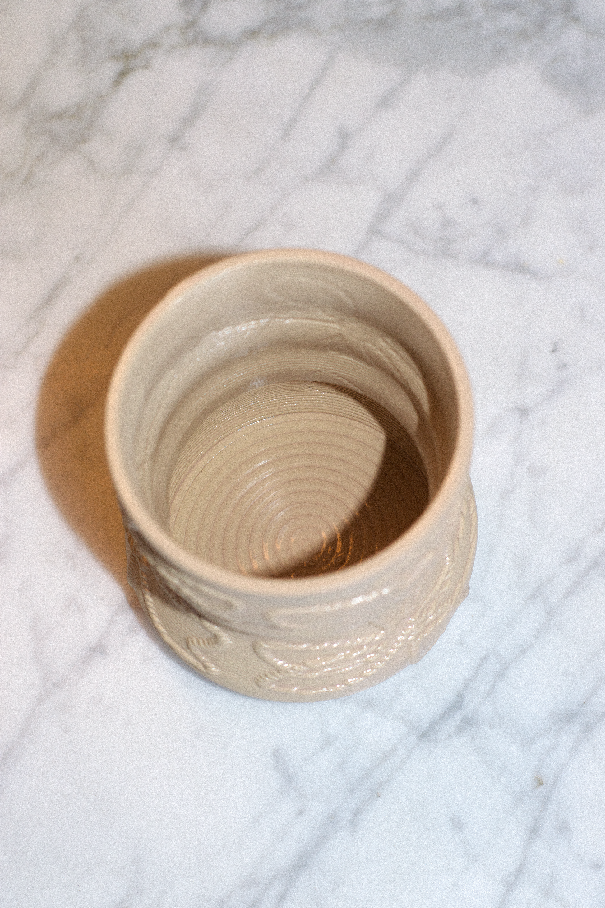 Top-down view of a cashew 3D-printed clay matcha cup by GLINA3 on a marble surface, highlighting the unique spiraled texture on the inside bottom.